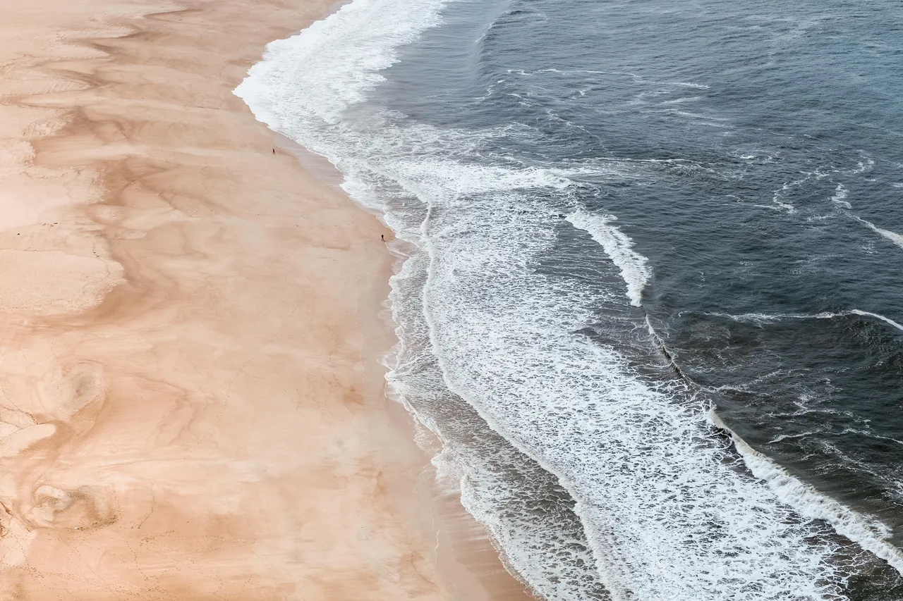 A beach with waves crashing on the shore