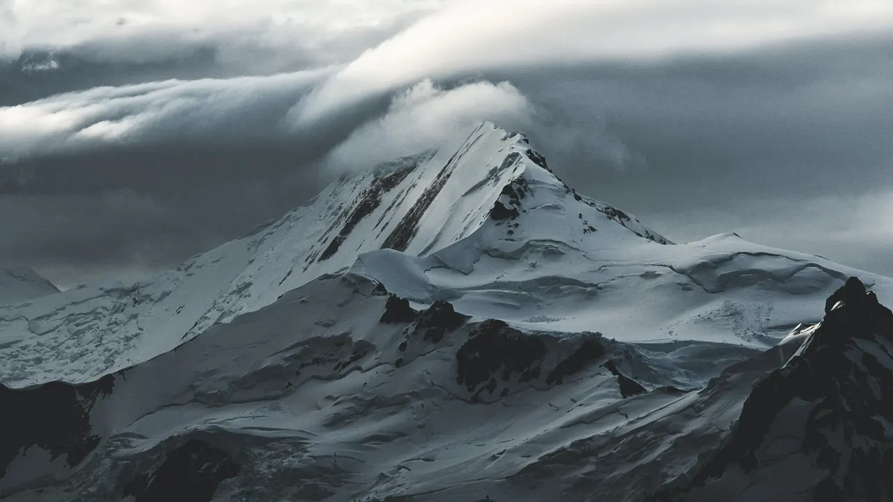 A snowy mountain with clouds above