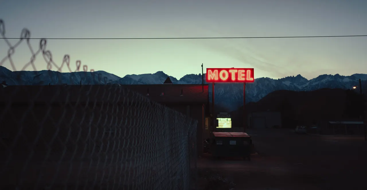 A motel sign with a snowy mountain in the background