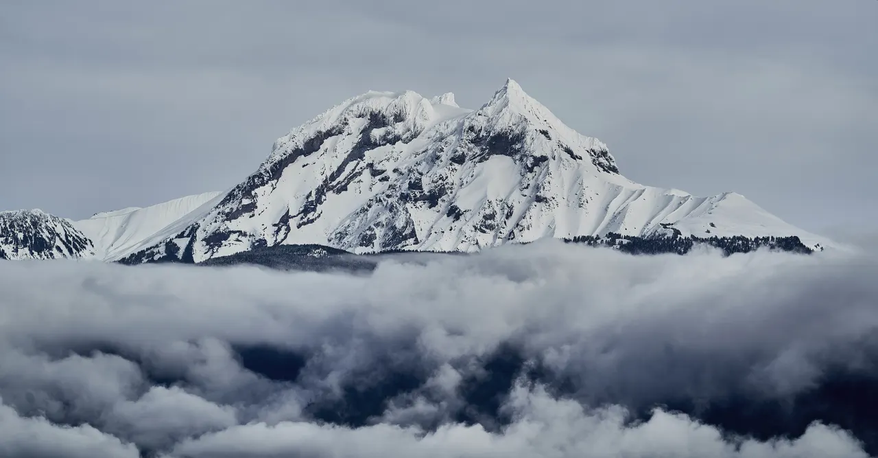 A mountain with snow and clouds