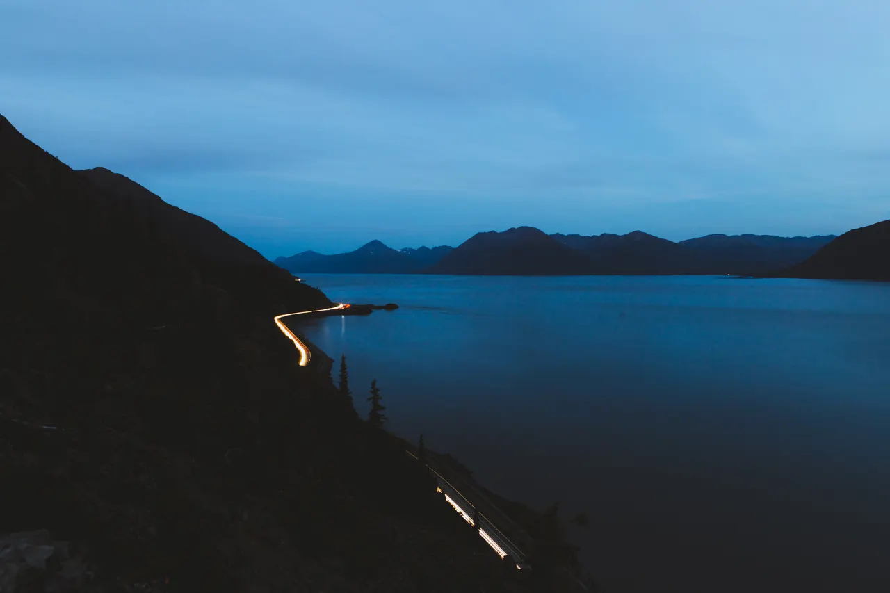 A road with lights on the side of a body of water
