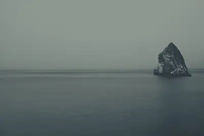 A large rock in the middle of a body of water