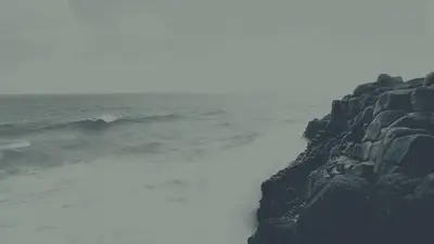 A person standing on a rocky cliff by the ocean