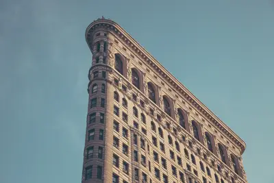 A tall building with many windows with Flatiron Building in the background