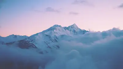 A mountain with snow and clouds