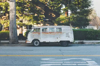 A rusty van parked on the side of a road