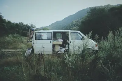 A van in a field with a bicycle and a mountain in the background
