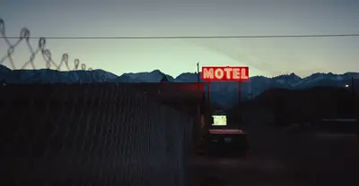 A motel sign with a snowy mountain in the background