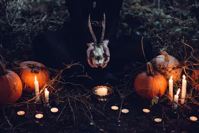 A person holding a skull and pumpkins