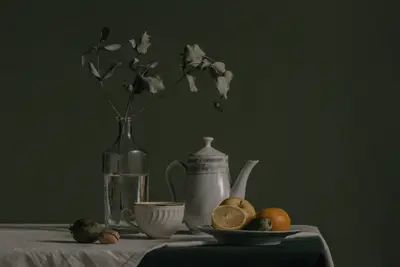 A table with a vase of fruit and a pitcher of water