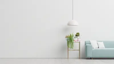 A white wall with a blue couch and a lamp