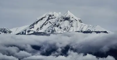 A mountain with snow and clouds