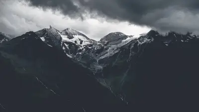 A snowy mountain tops with clouds in the background
