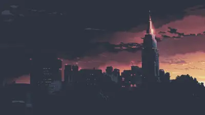 A city skyline with a tall building and a red sky