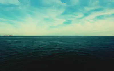 A large body of water with clouds in the sky
